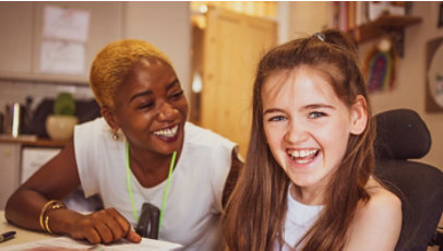 An adult and a child smile inside a room.