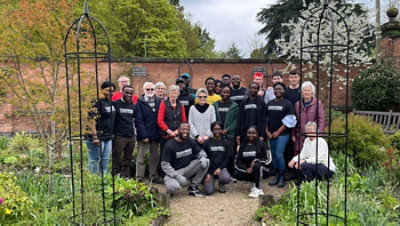 A group of volunteers posing along with church members in a garden.