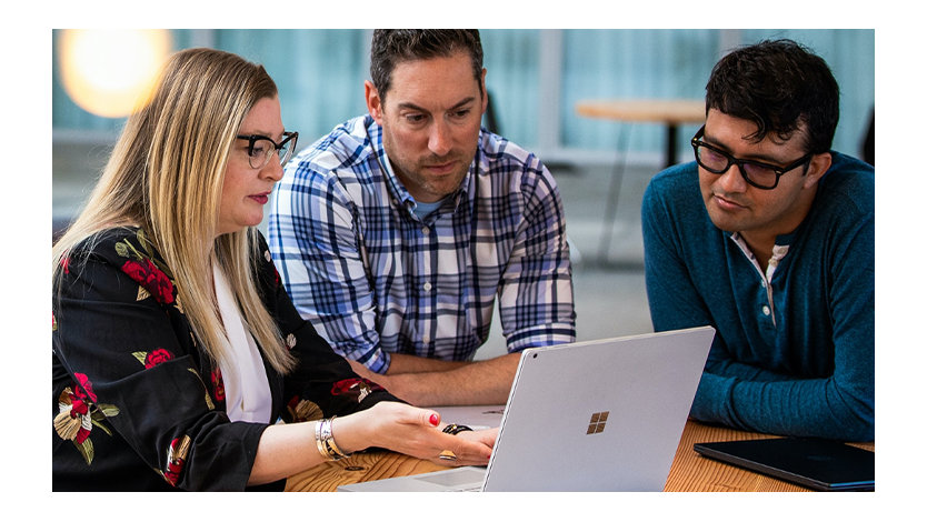 Three coworkers collaborating on a windows laptop