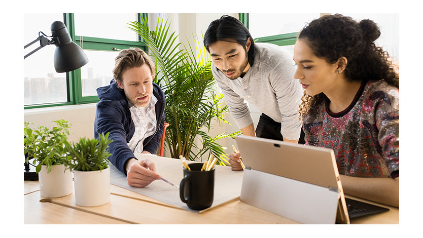 Trois collègues dans un bureau travaillent sur un appareil Surface posé sur un bureau