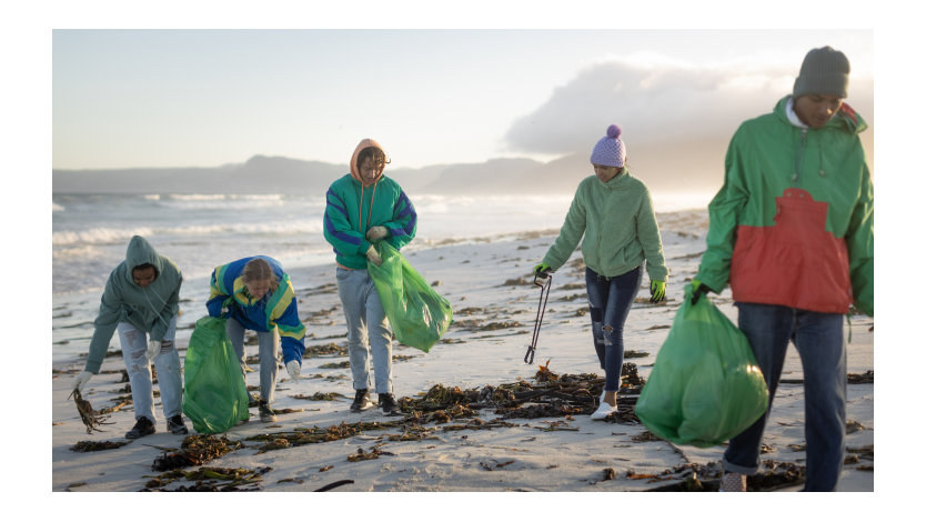 Een groep van vijf jonge vrijwilligers maakt een strand schoon.