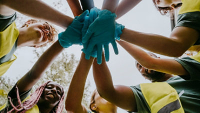 Un grupo de voluntarios de pie en un círculo y uniendo las manos.
