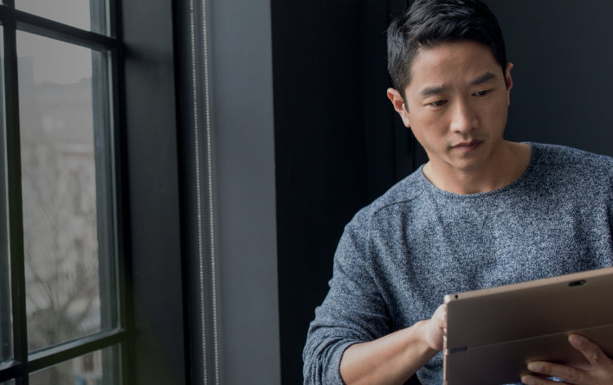 Nahaufnahme einer Geschäftsperson an einem Fenster, die ein Tablet benutzt.