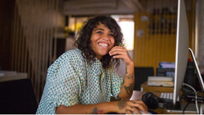 Portrait of a person smiling, using a computer.