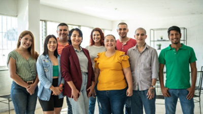 A team of nine, diverse coworkers smiling at the camera.
