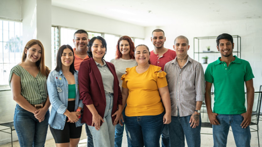 A team of nine, diverse coworkers smiling at the camera.