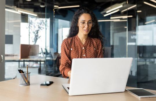 A female cybersecurity specialist working on a laptop in a modern office.