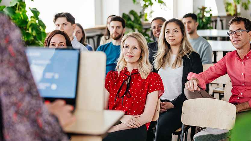 A group of people attentively listening to a presenter.