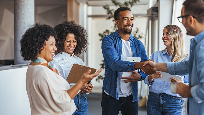 Colleagues smiling and shaking hands in an office.