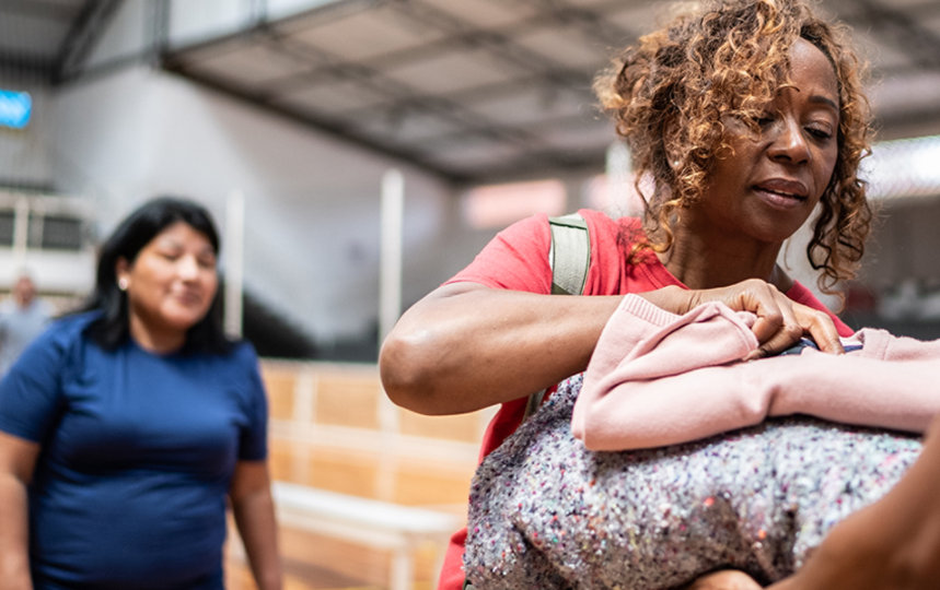 Femme recevant une couverture d’un soldat dans un centre communautaire.