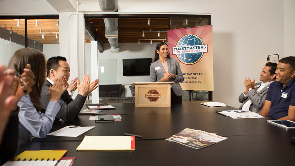 A speaker receiving applause at a Toastmasters meeting.