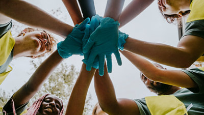 Team huddle with gloved hands stacked together outdoors.