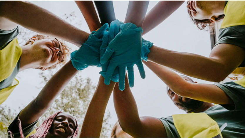A group of volunteers standing in a circle and putting their hands together.