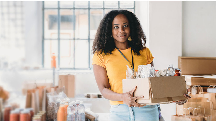 Volunteer woman holding a box of food and drinks