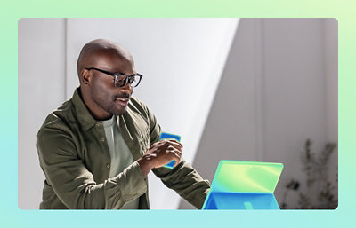 A man holding a tea cup and looking into laptop screen.