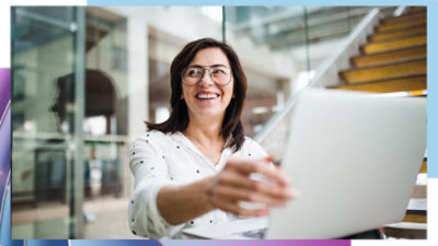 A women smiling while holding her laptop screen.