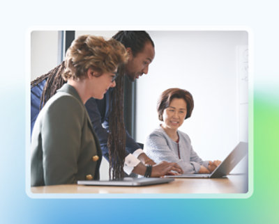 Parlak bir ofis ortamında bir dizüstü bilgisayar üzerinde gülümseyen ve tartışan üç profesyonel.