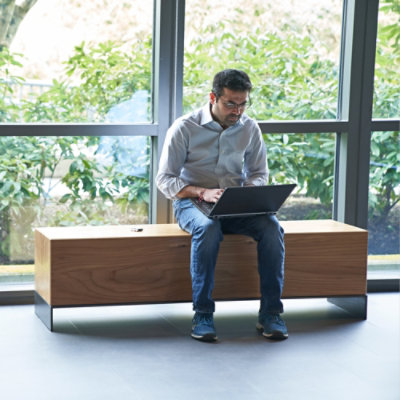 A man sitting on a bench using a laptop.