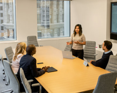 一個人站在一群坐在桌前的人前面