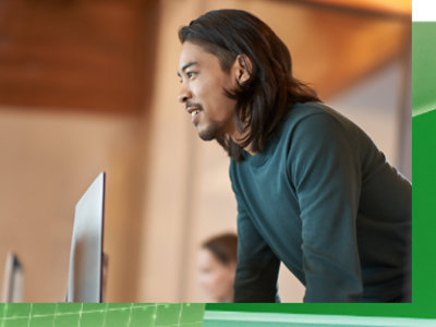 a person is standing and leaning over his laptop