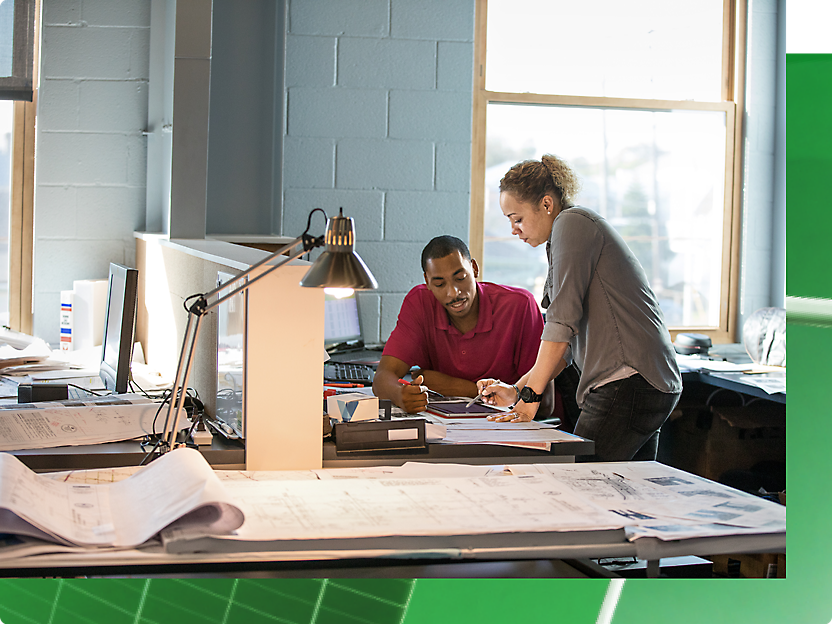 Two people working in an office with a green background.
