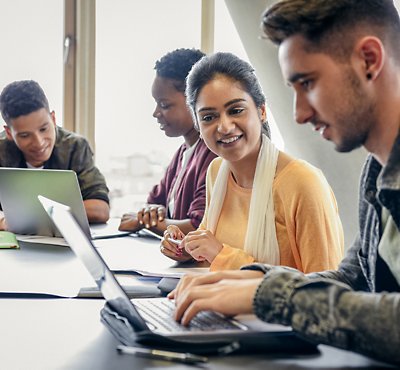A group of people sitting at a table looking at a computer