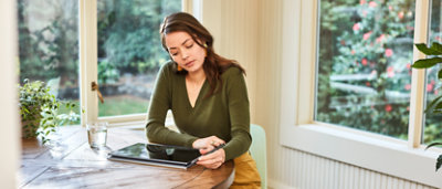 A woman sitting at a table with a tablet computer.