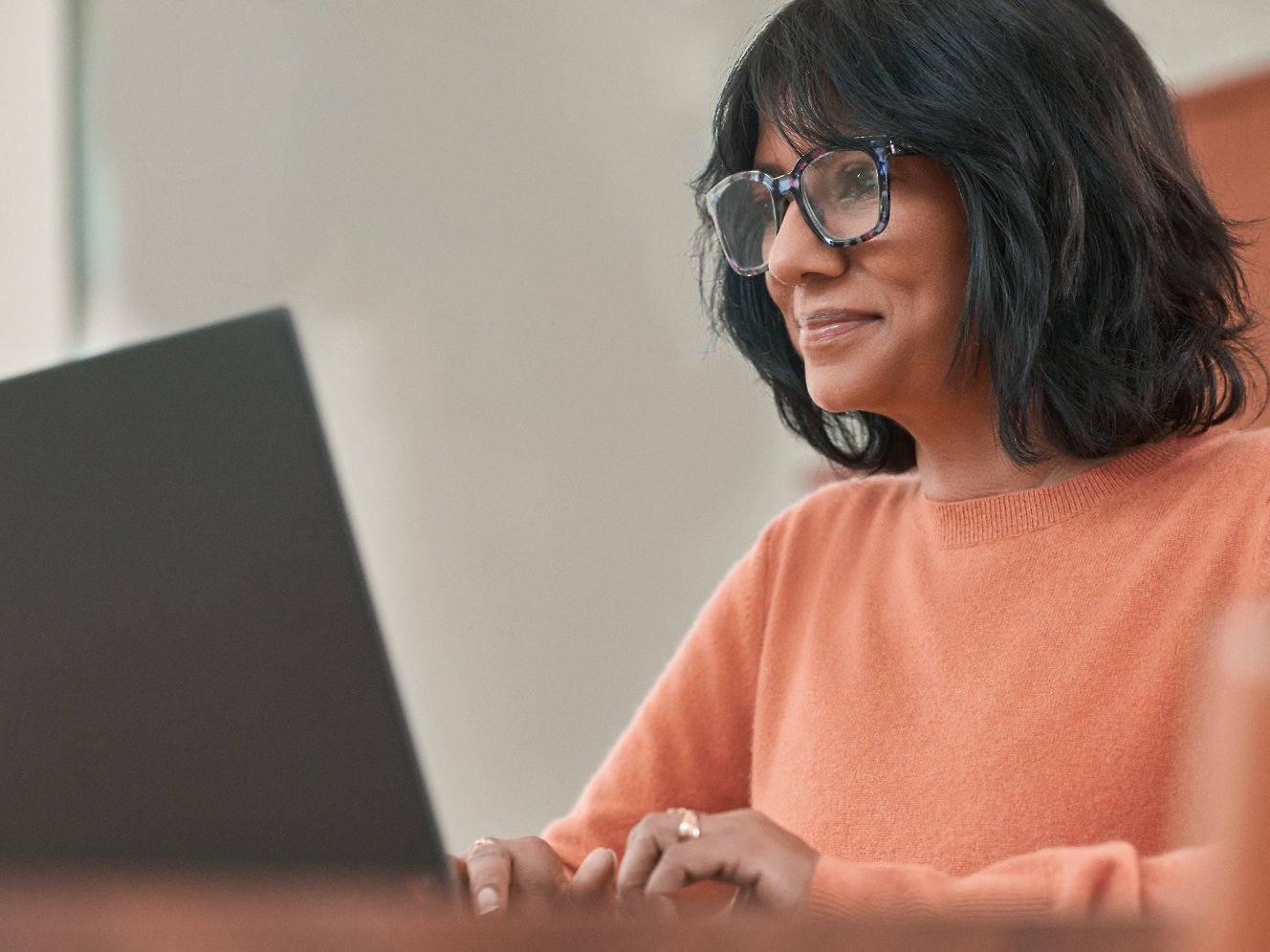 Eine Frau mit Brille, die mit einem Laptop arbeitet
