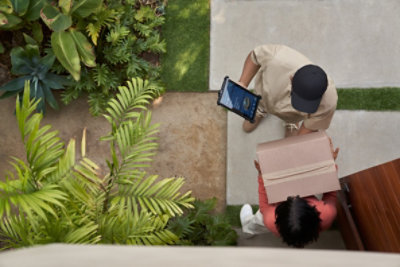 Delivery man dropping off a box at a woman’s front door.