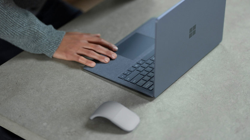 A person’s hand touches a Microsoft Surface laptop.