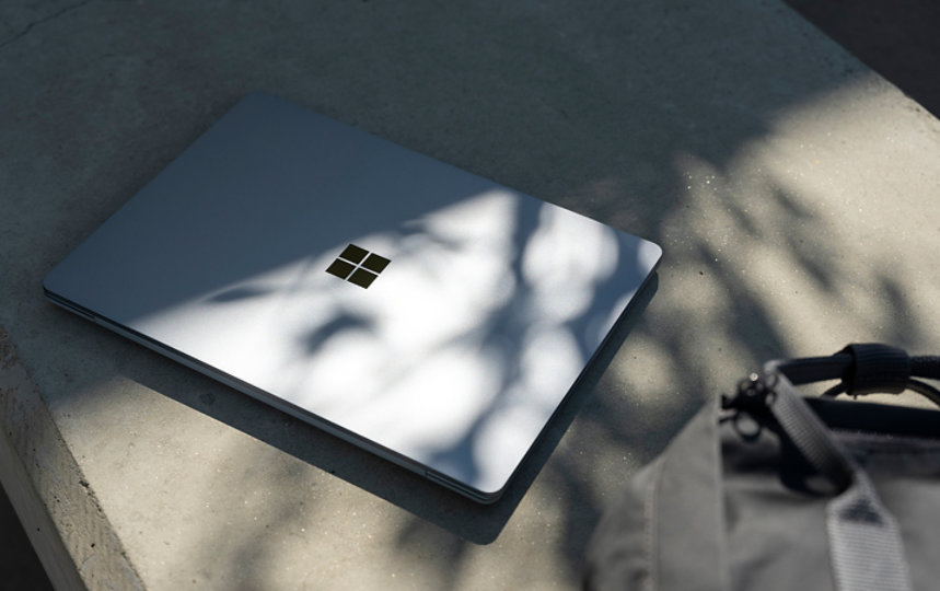 Un Surface Laptop Go posé sur un banc en béton, non loin d’un sac à dos