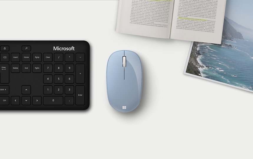 Microsoft Bluetooth® Mouse next to a keyboard, book, and magazine.