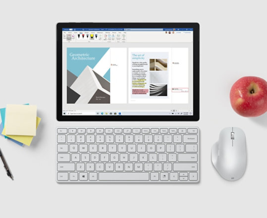Le clavier compact Microsoft Designer placé devant un écran de tablette à côté d’une souris Microsoft, de morceaux de papier et d’un stylo.