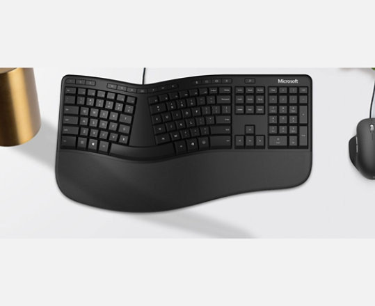 A curved Microsoft Ergonomic Keyboard and contoured mouse on a desk.