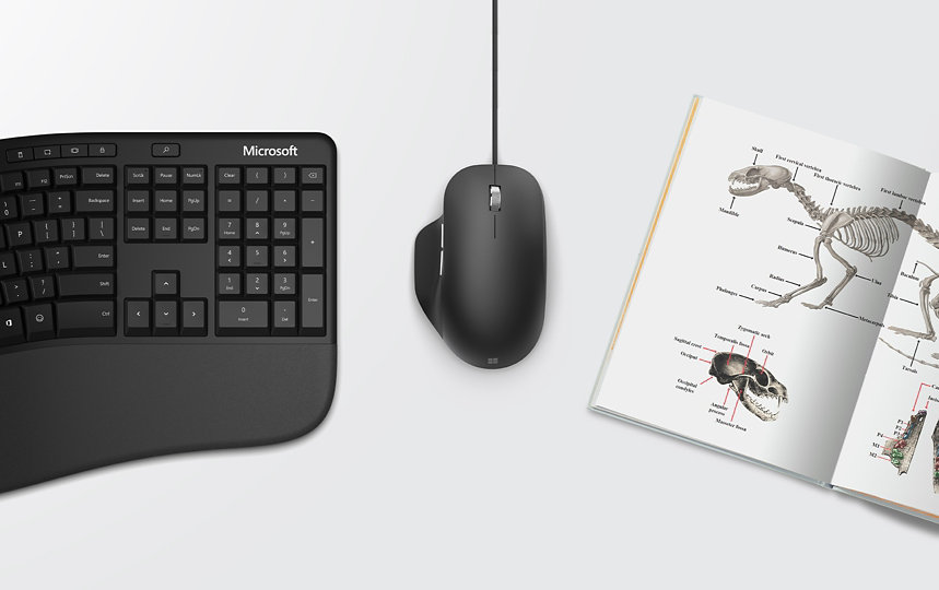 Microsoft ergonomic keyboard and mouse beside a book.