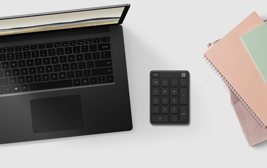 Microsoft wireless Number Pad next to a laptop and a day planner.