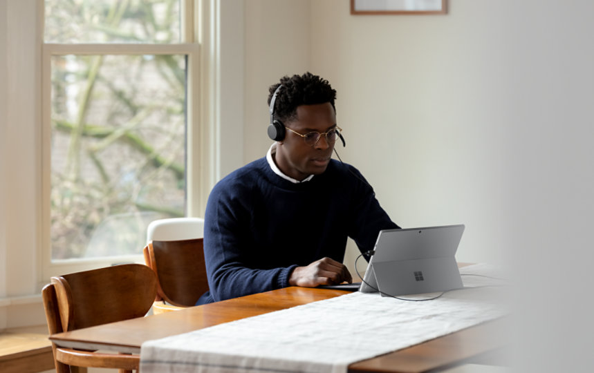 A person with the Microsoft Modern USB Headset plugged into a Surface device.