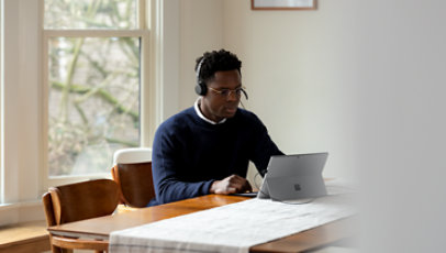 Une personne portant le casque USB Microsoft Modern branché à un appareil Surface.