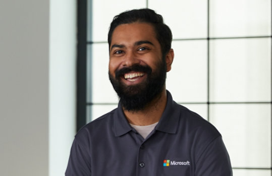 A friendly looking support professional wearing a Microsoft shirt and smiling.
