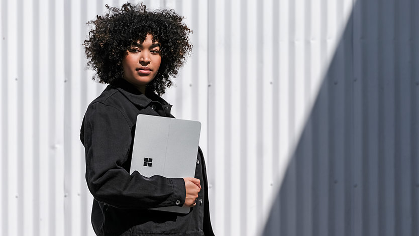 A person holding the Surface Laptop outside.