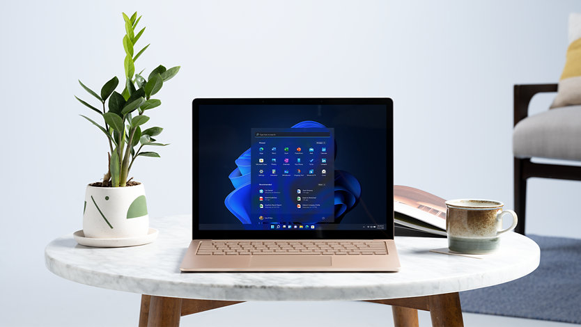 Ein Surface Laptop auf einem Tisch mit Windows 11 und anderen Symbolen.