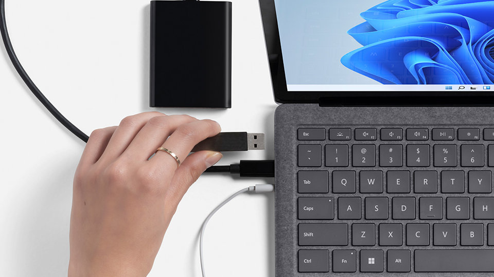 A user connects multiple cables to the Surface Laptop 4.