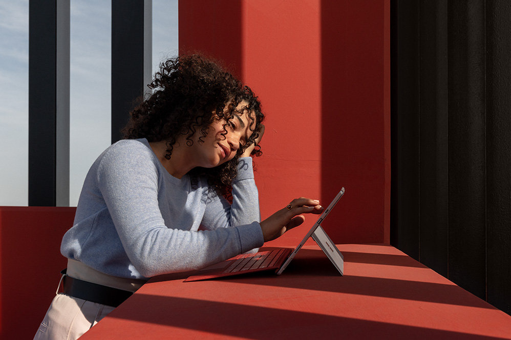 Eine Person tippt auf den Bildschirm des Surface Pro 7 mit angeschlossenem Type Cover..