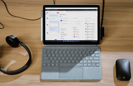 An open Surface Go 3 laptop with headphones connected and mouse nearby.