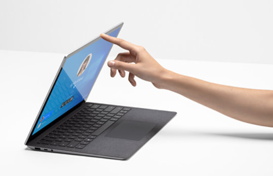 La mano de una persona con el dedo que levanta la funda de Surface Laptop 4 para empresas.