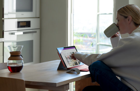A person seated at a desk working with a Surface Pro 7 plus propped up on a kickstand.