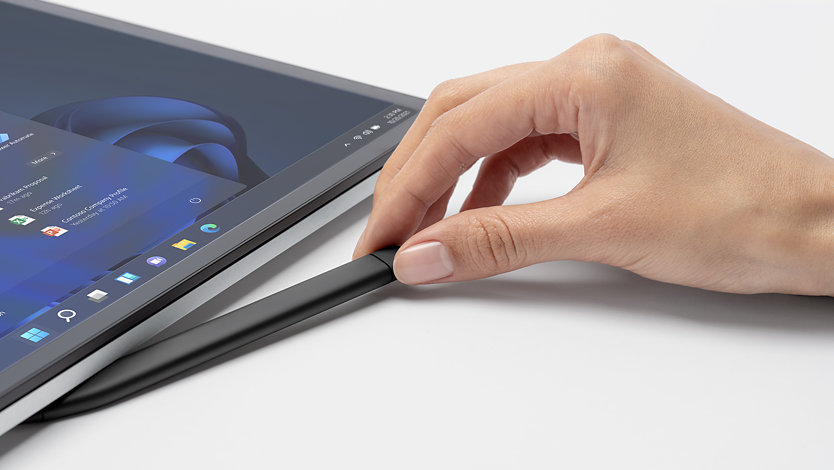 A hand pulling a Slim Pen 2 from its dock on the side of a Surface Laptop Studio for Business.