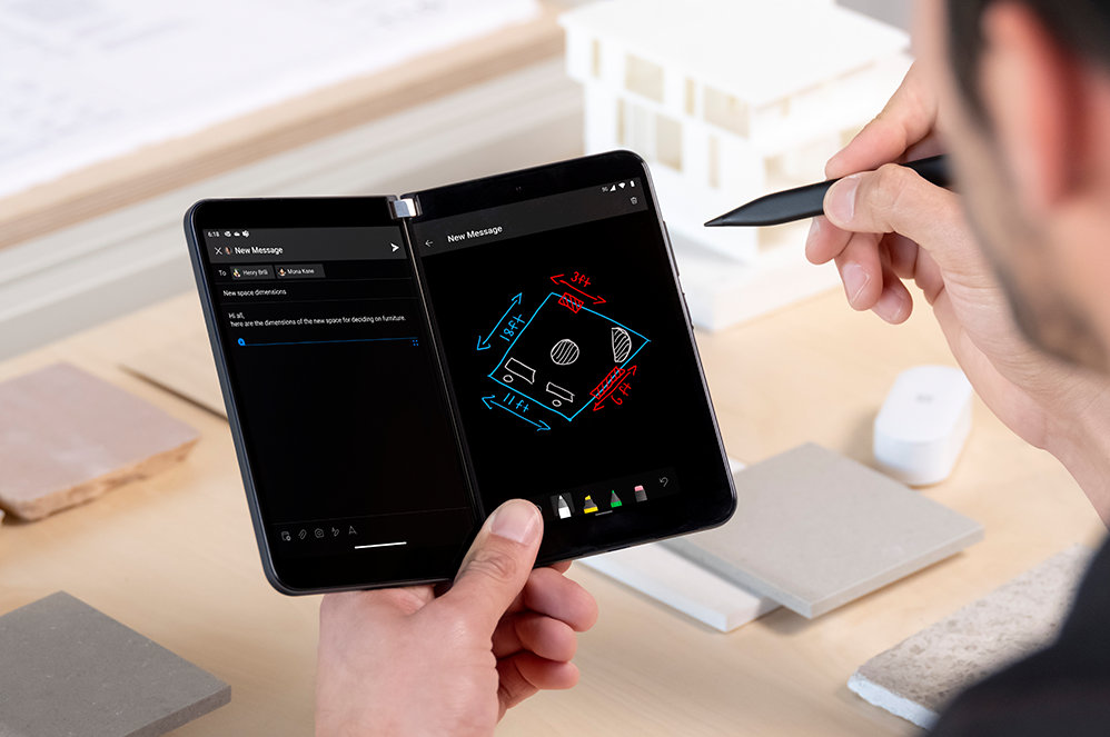 Iemands hand houdt een Surface Duo 2 voor zakelijk gebruik vast, met een Surface Pen in de andere hand.