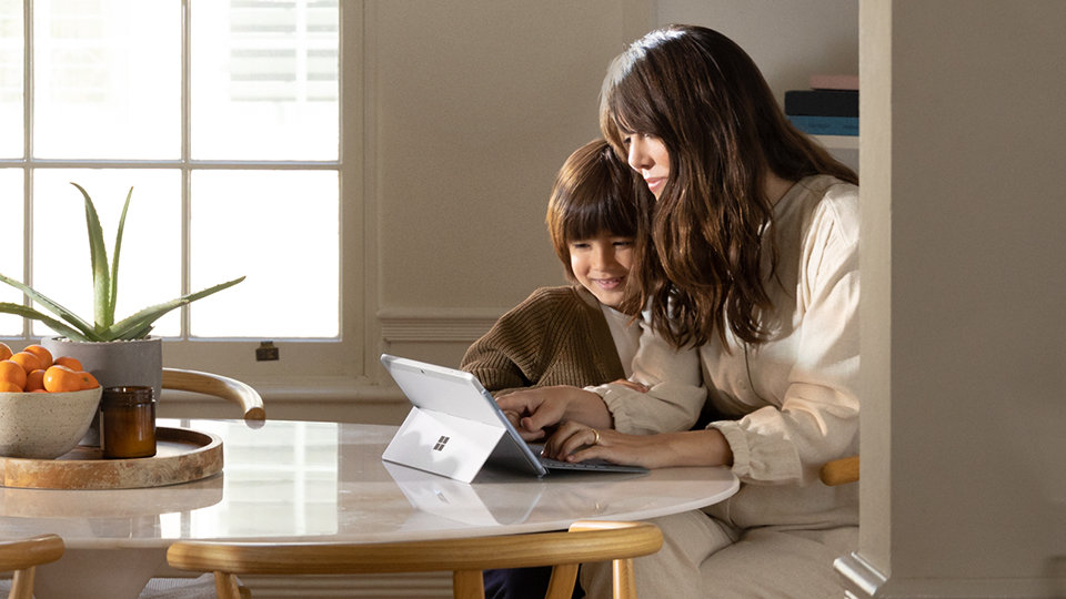 A woman and child use Surface Go with a Type Cover attached.