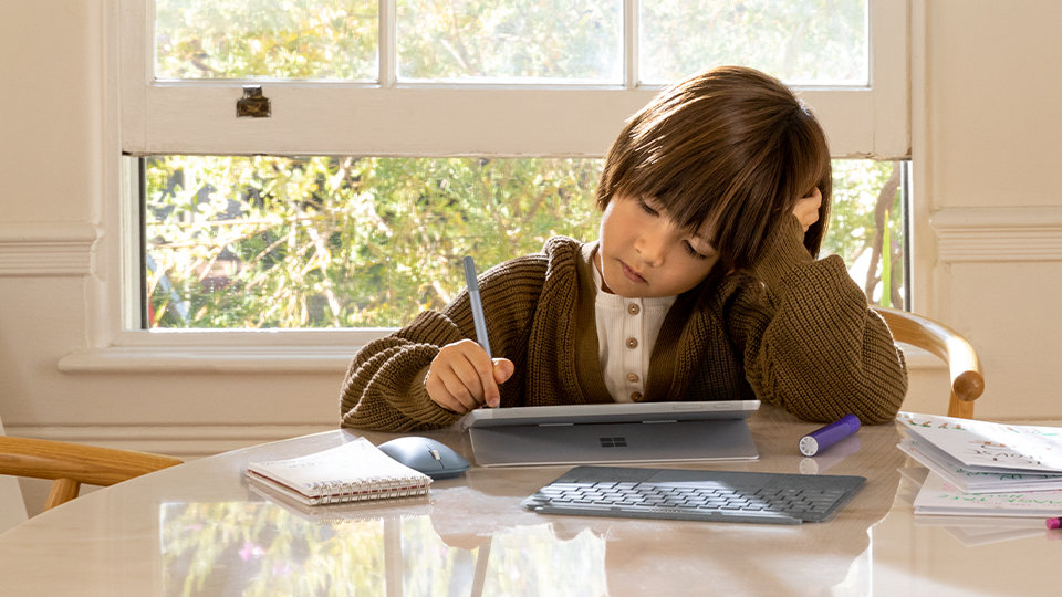 Een man aan tafel houdt een Surface Go 2-scherm vast